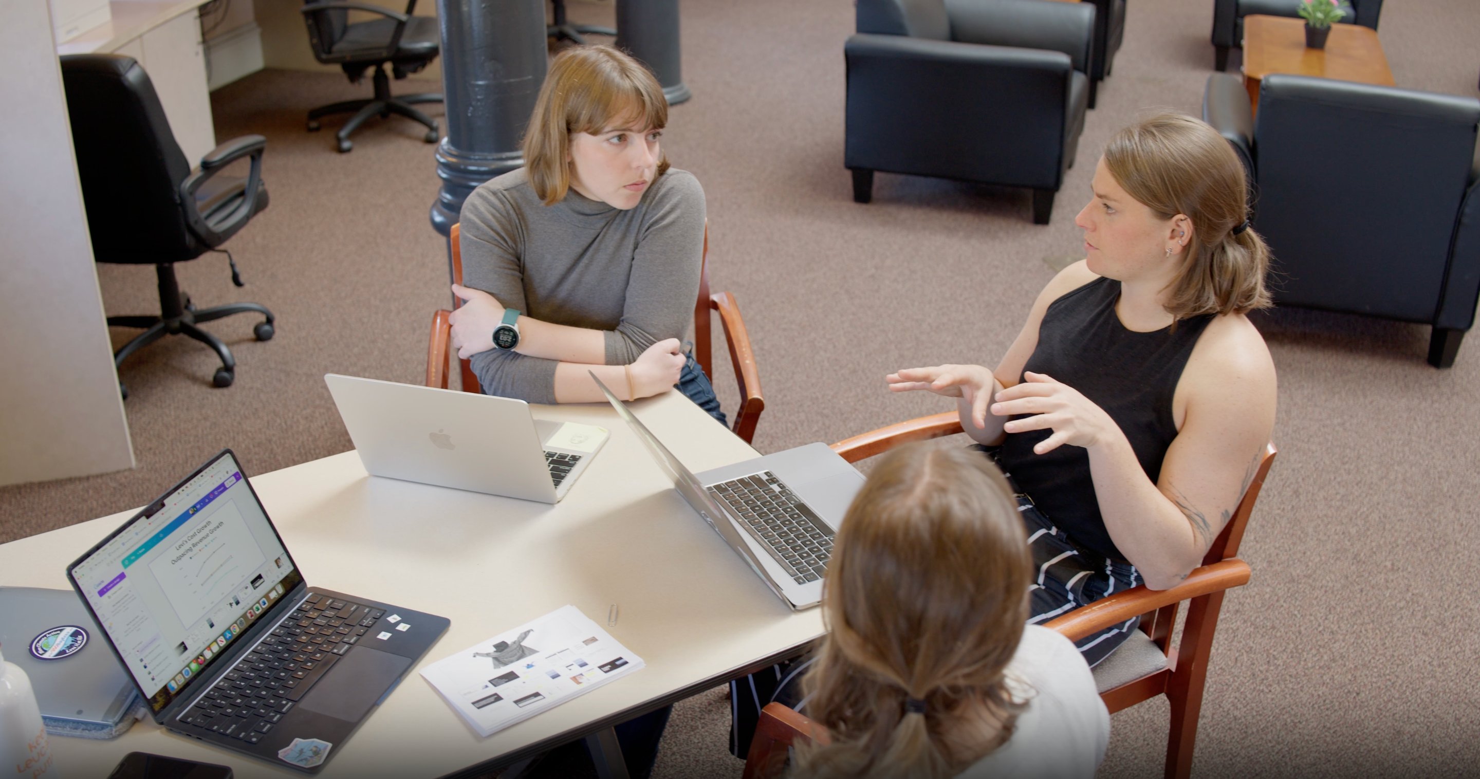 a group of women sitting at a table with laptops