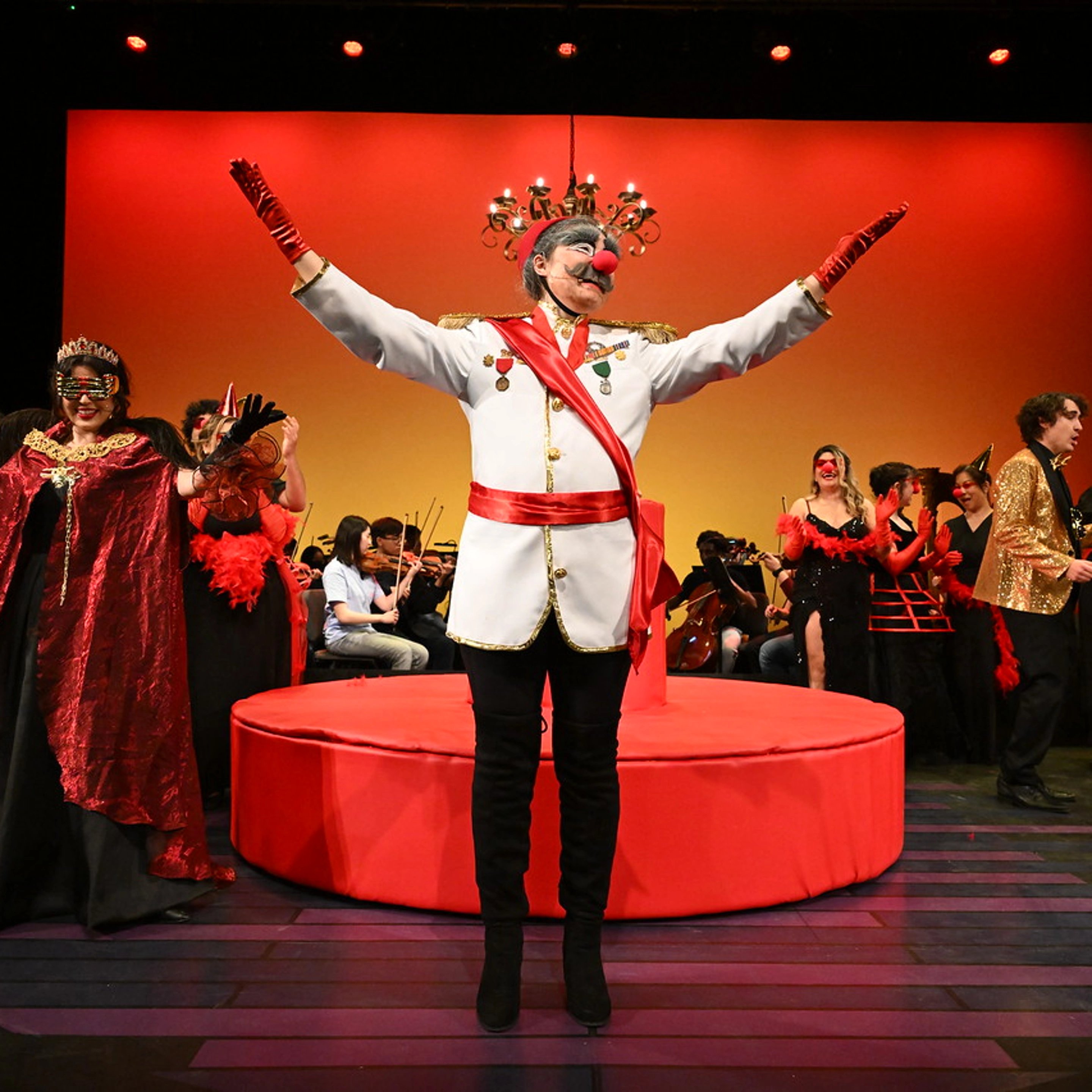 a man wearing a mask and gloves on a stage with people in the background