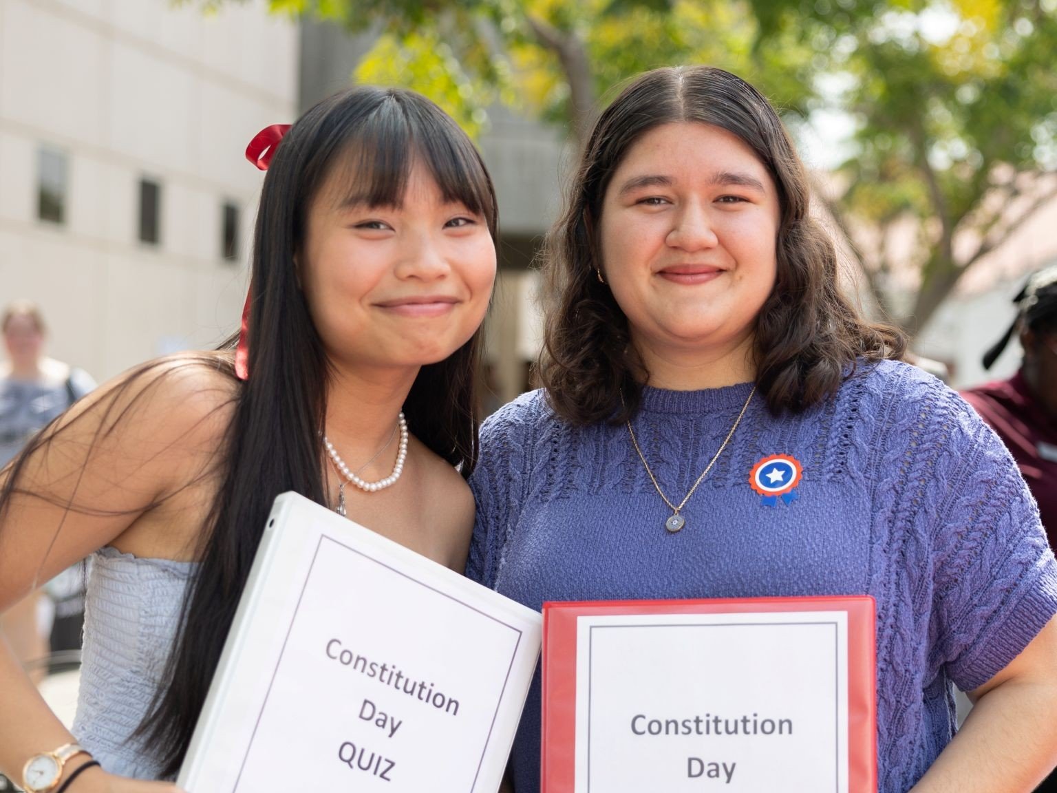 two women holding signs posing for the camera