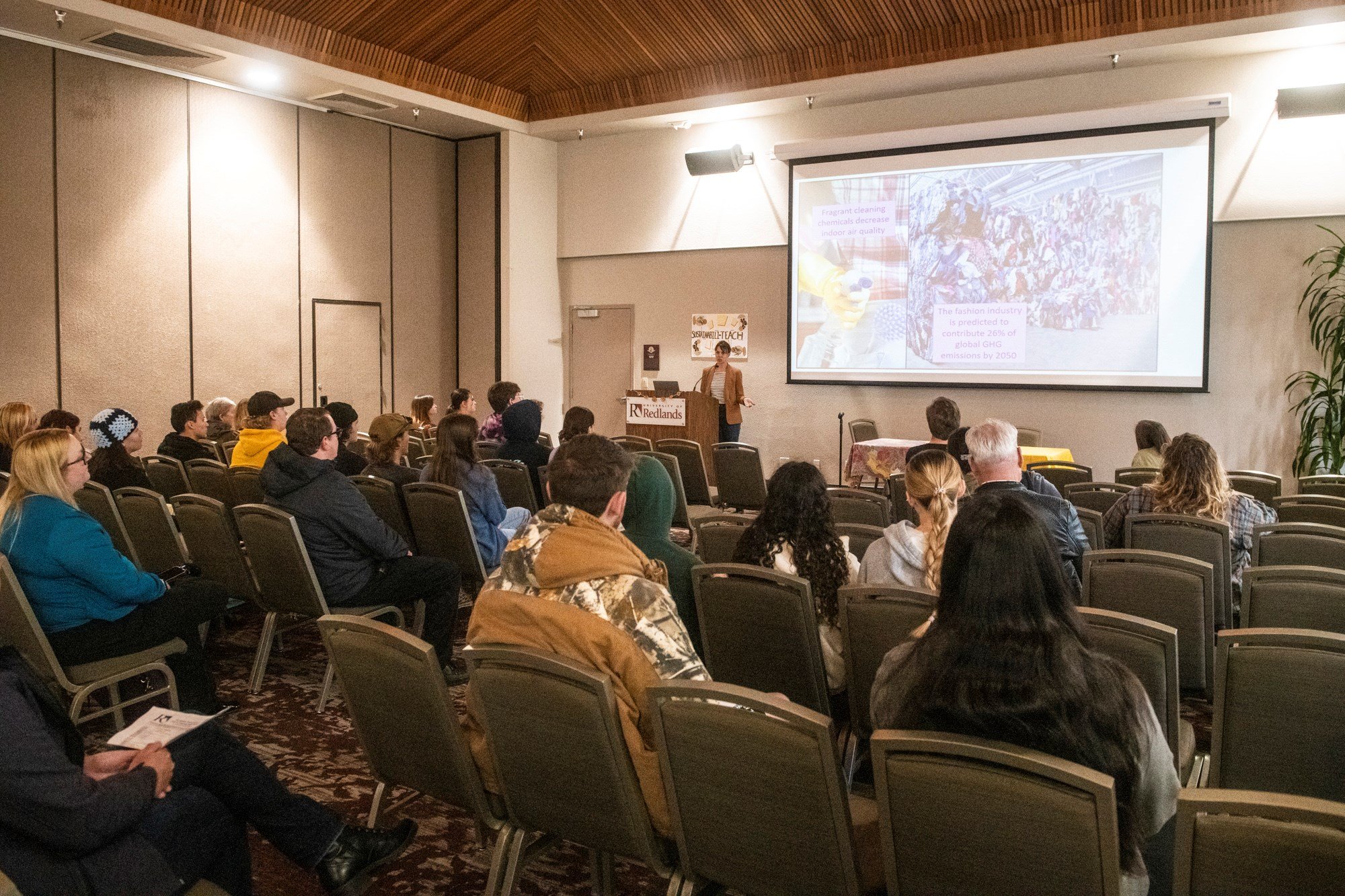 a group of people sitting in chairs in a room with a screen