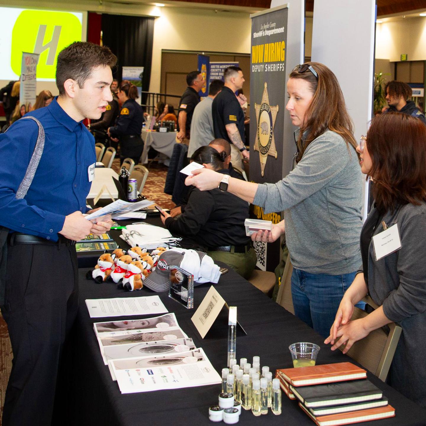 a man standing next to a table with a woman standing next to a table with other people