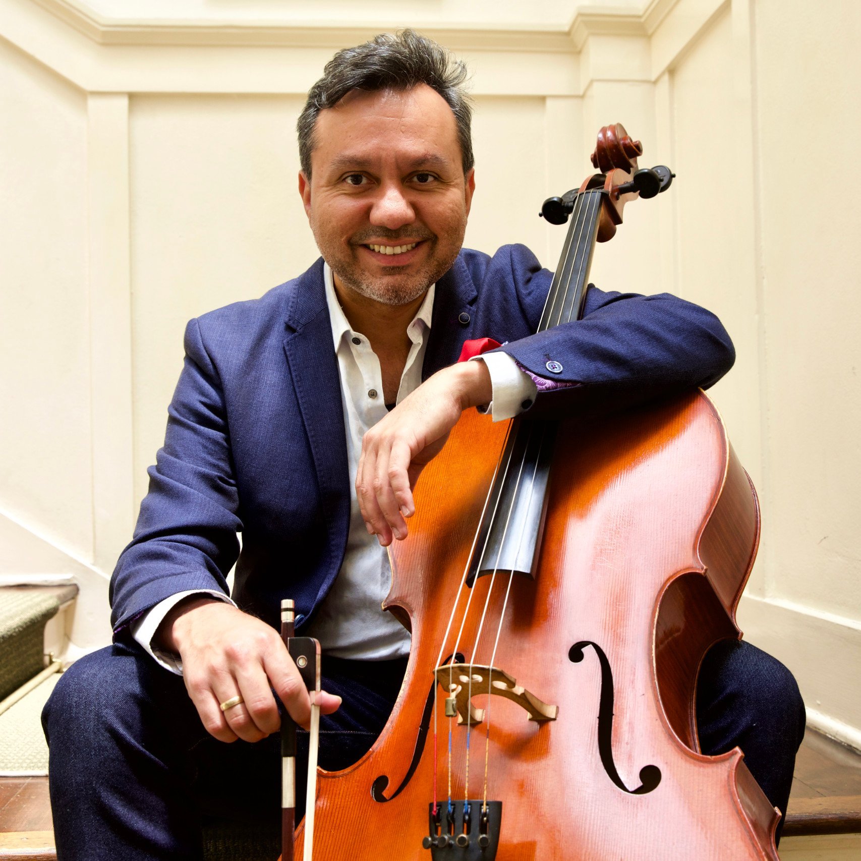 a man sitting on stairs holding a cello