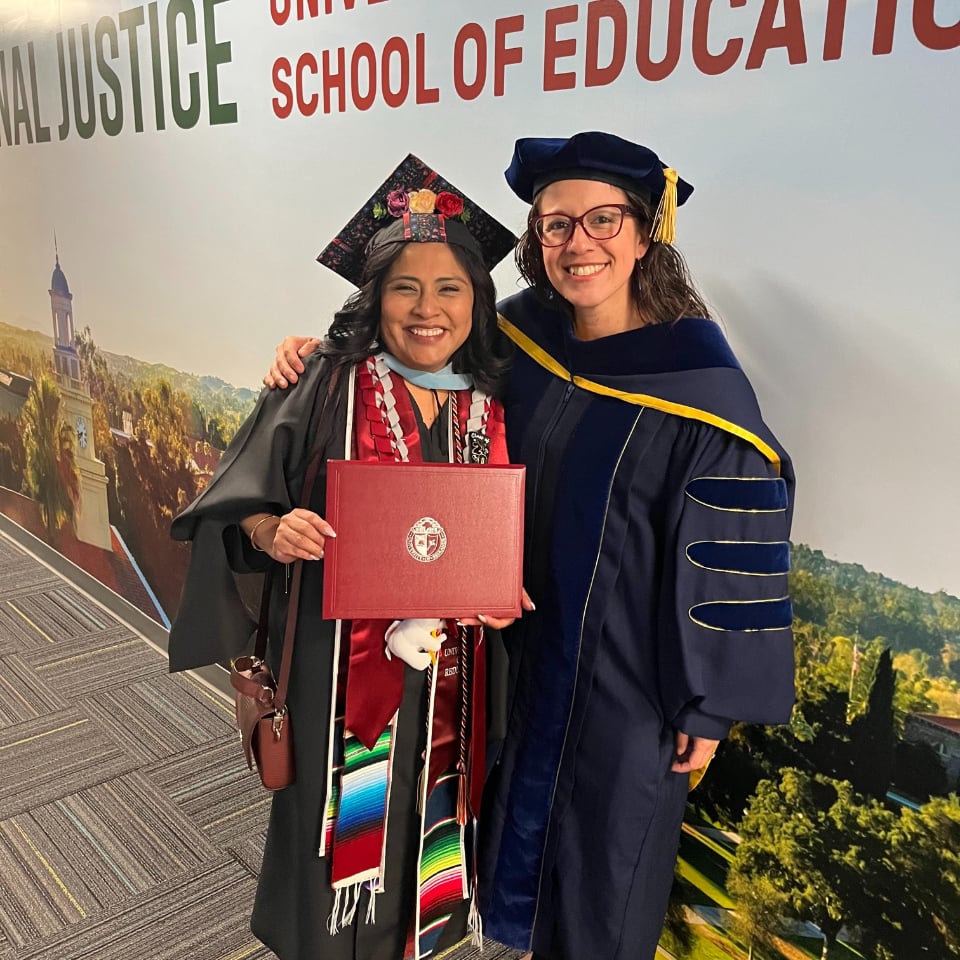 a woman in a graduation gown and cap holding a diploma