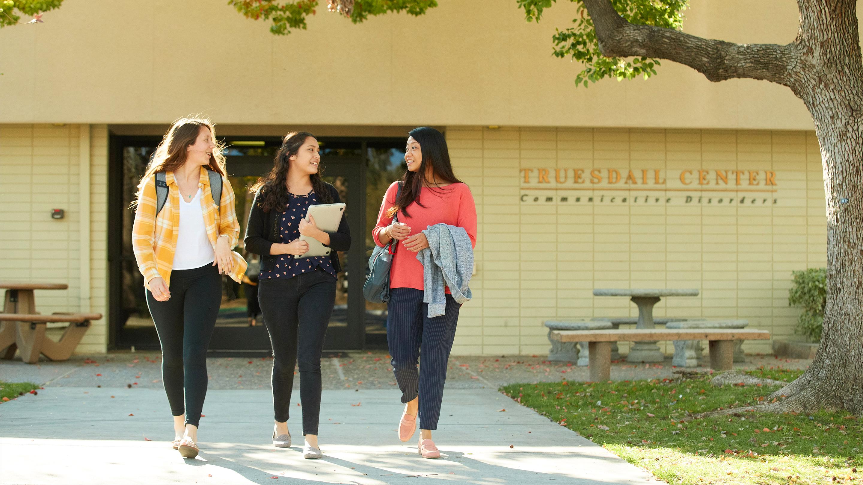 a group of women walking on a sidewalk