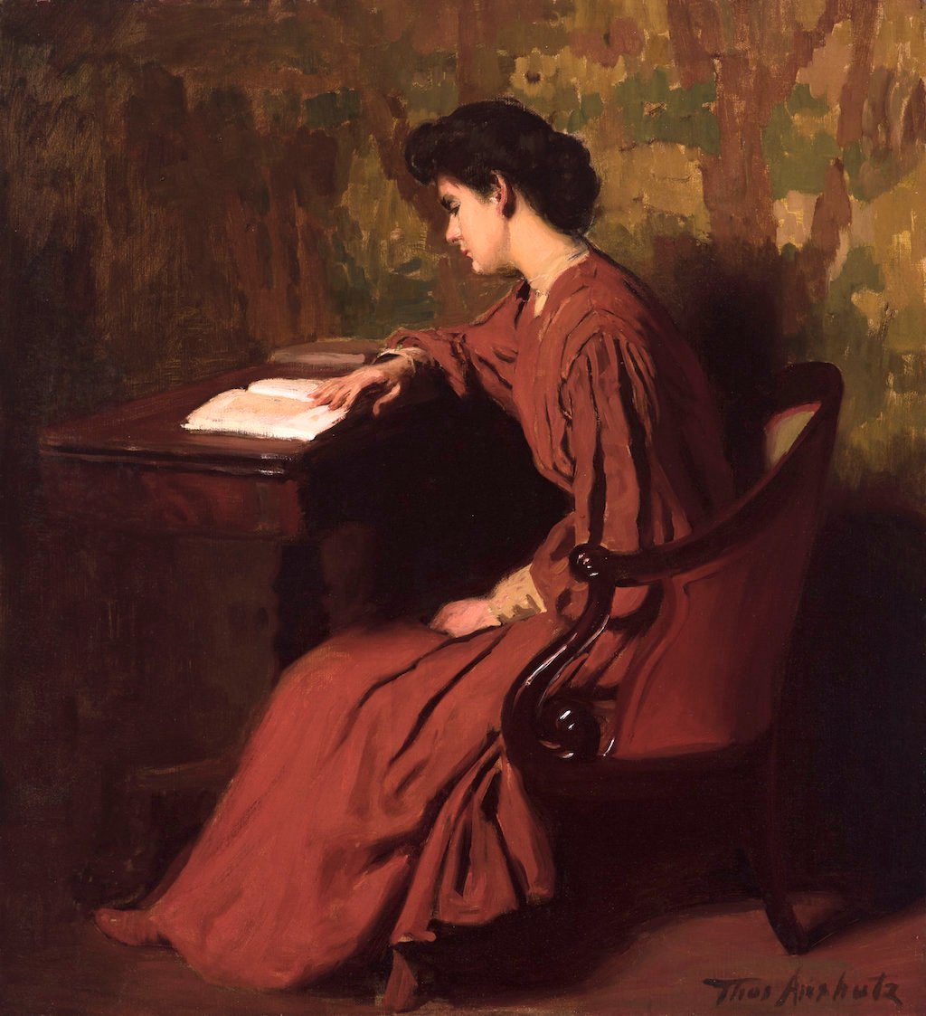 a woman sitting at a desk reading a book