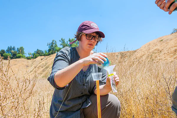 a person pouring liquid into a plastic container