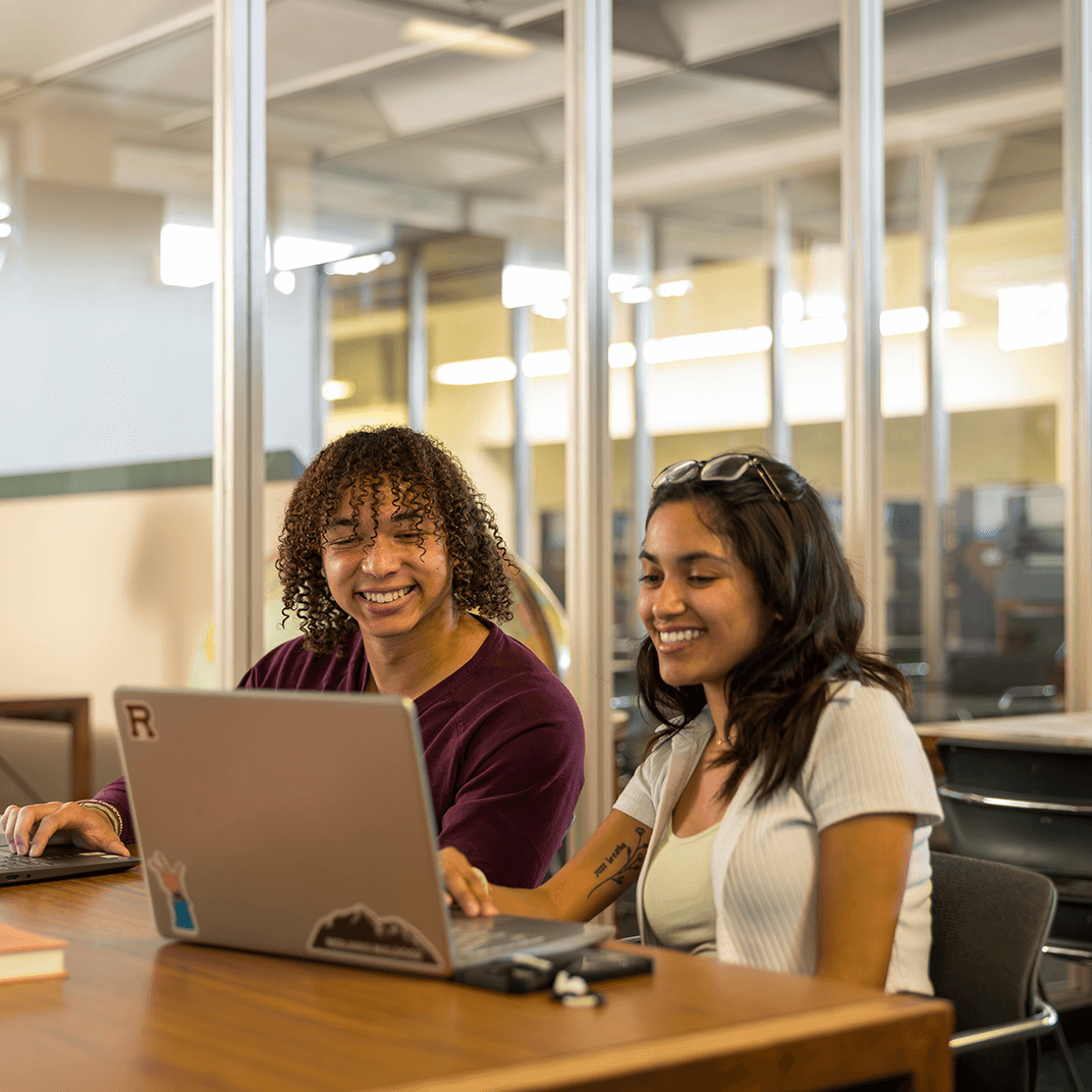 a couple of women sitting at a table with laptops