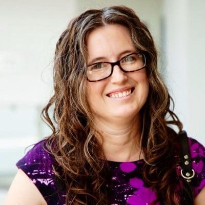 a woman wearing glasses and a purple dress