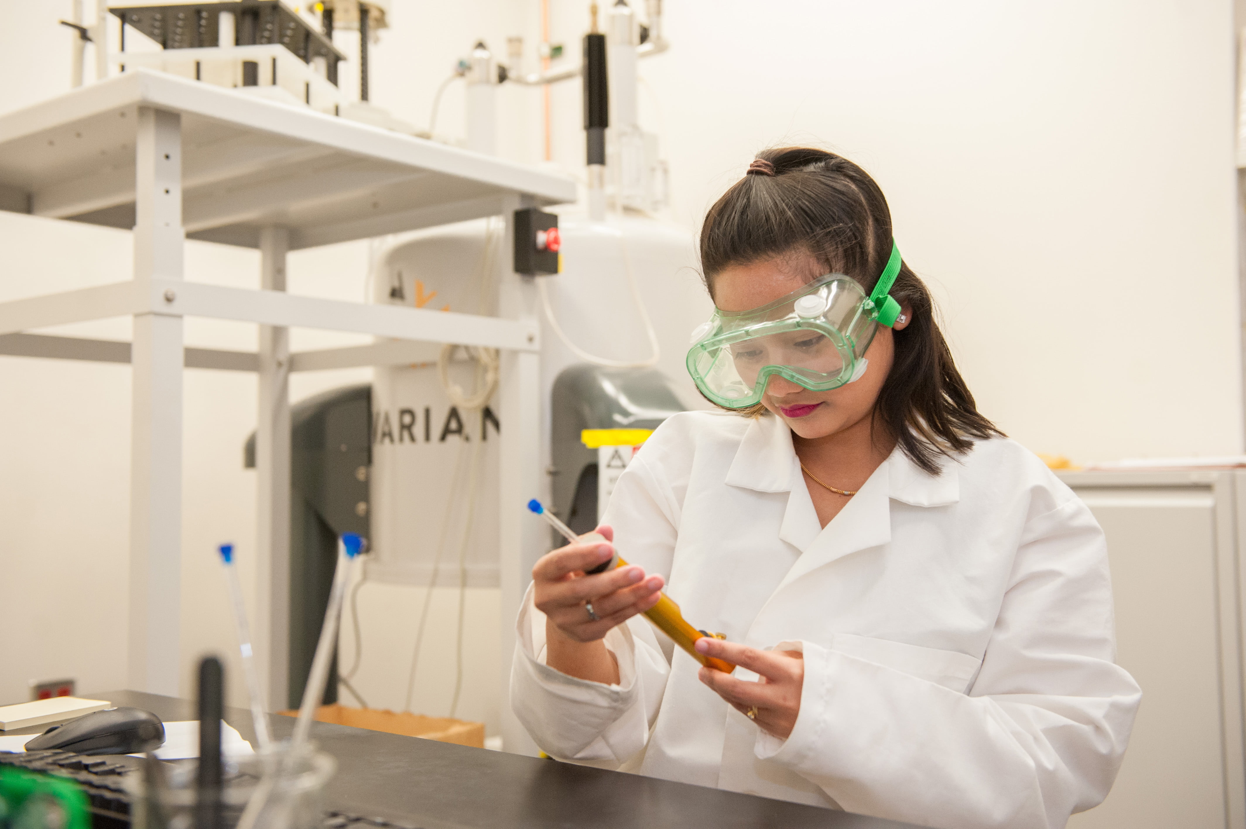 a woman wearing safety goggles and holding a tube