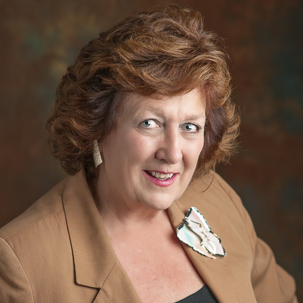 a woman with short brown hair wearing a brown jacket