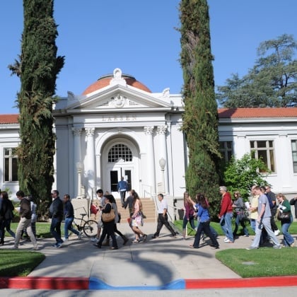 a group of people walking in front of a white building