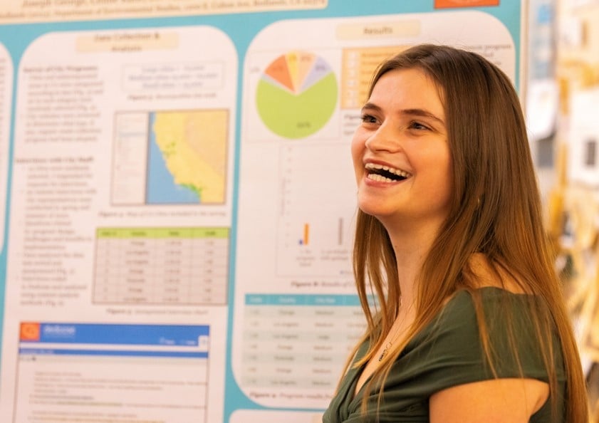 a woman smiling in front of a poster