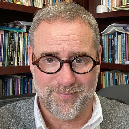 a man wearing glasses and smiling