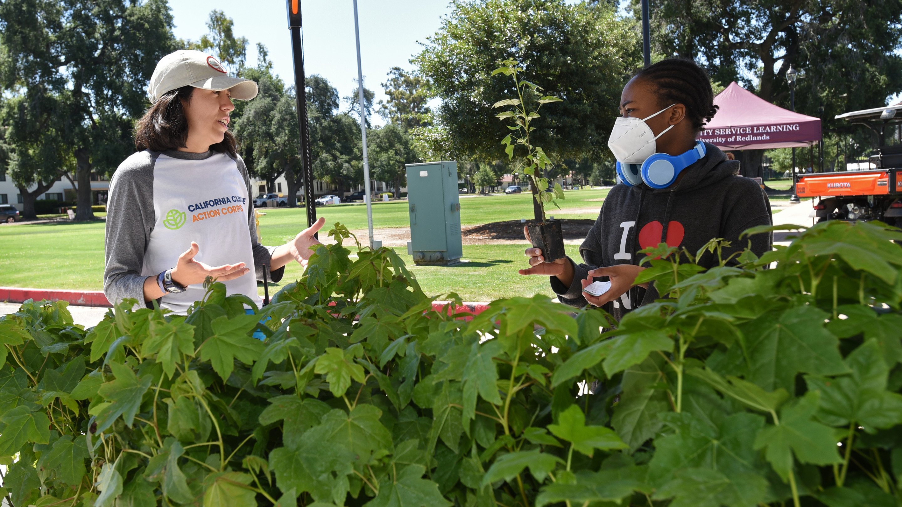 a woman wearing a mask talking to a young woman in a park