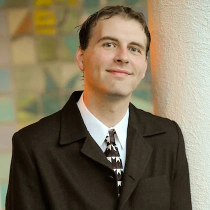 a man in a suit leaning against a pillar