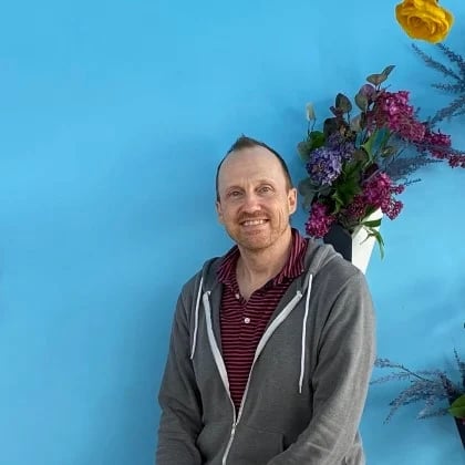 a man standing in front of a blue wall with flowers