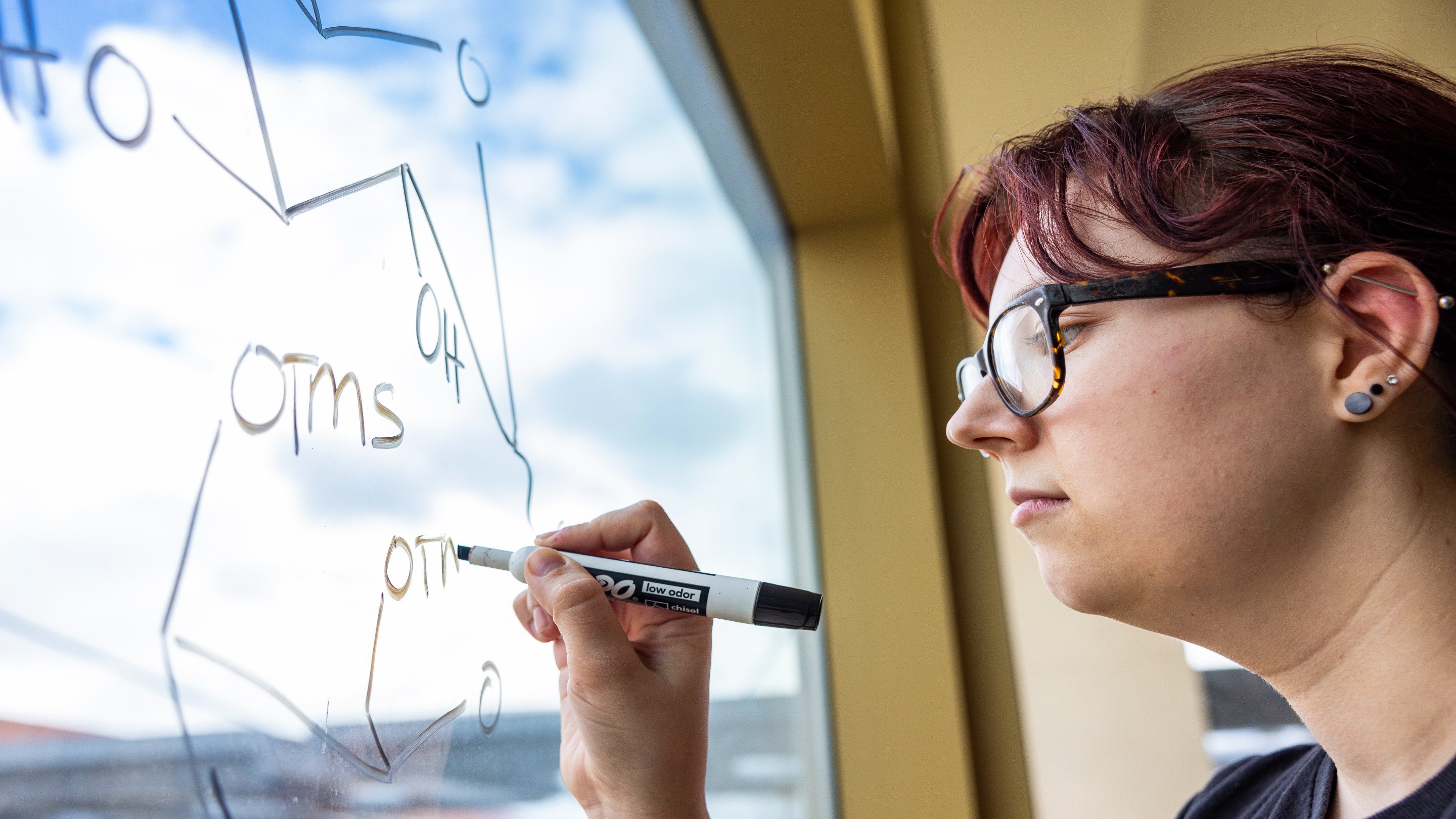 a woman writing on a glass board