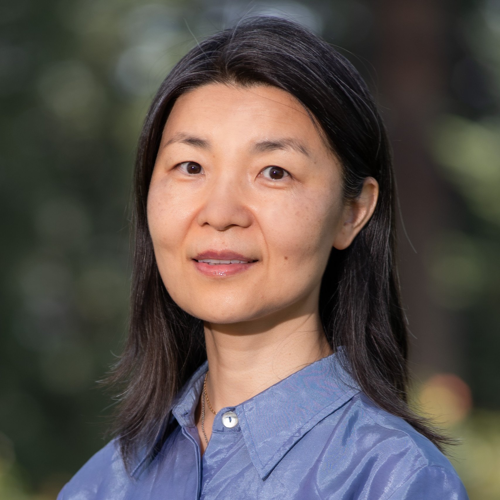 a woman with dark hair wearing a blue shirt