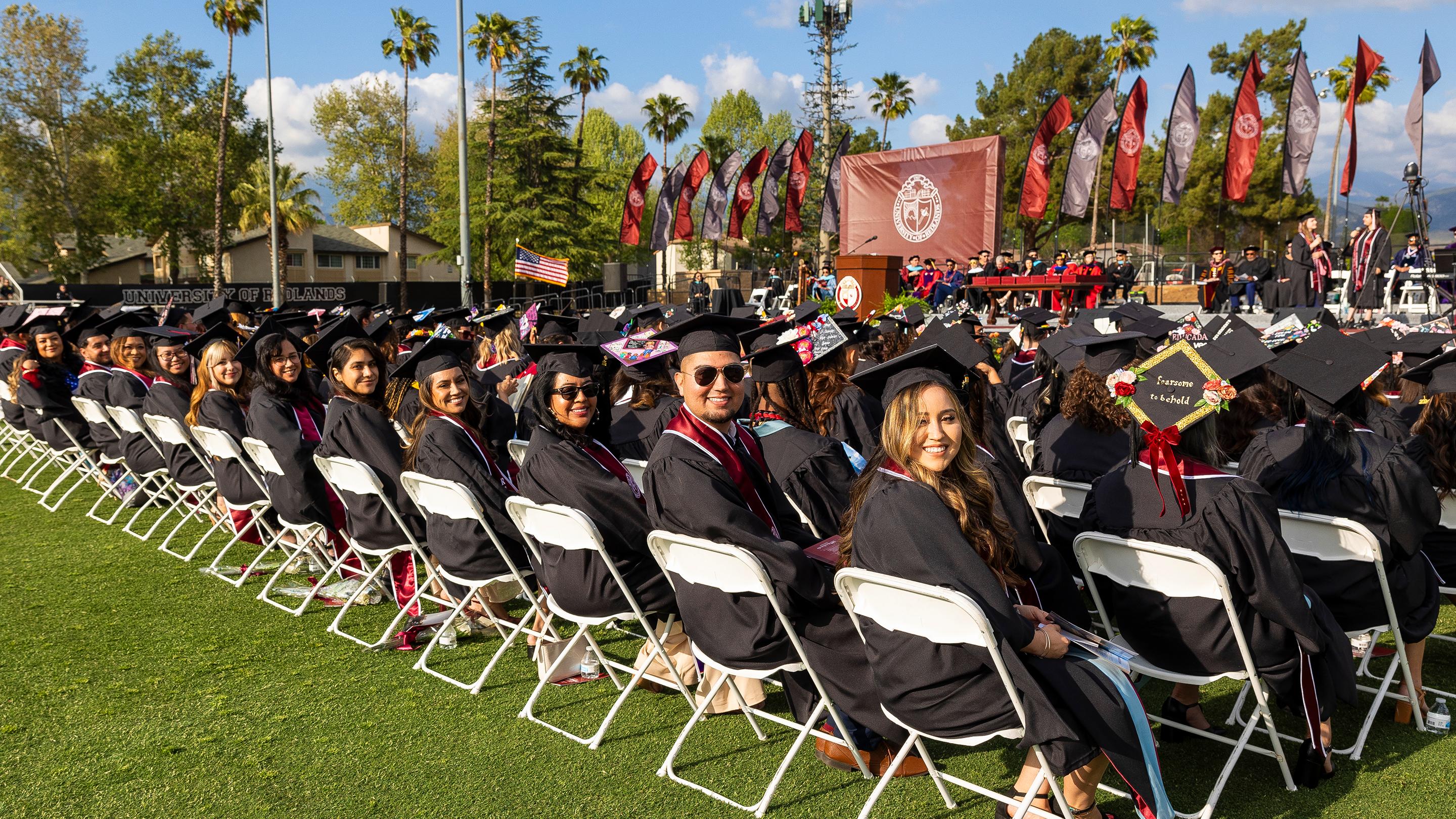 a group of people in graduation gowns and caps sitting in chairs