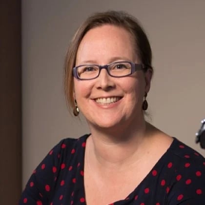 a woman wearing glasses and smiling