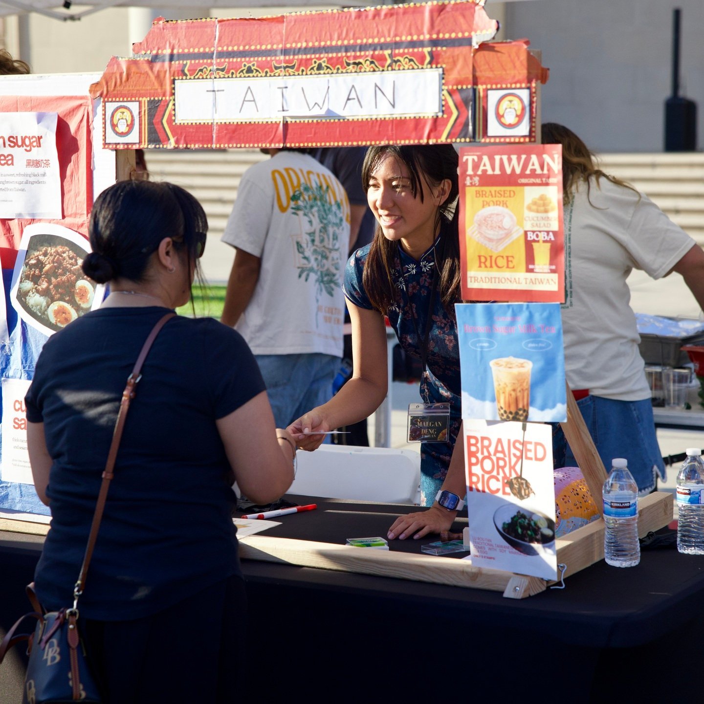 a woman shaking hands with a woman at a food stand