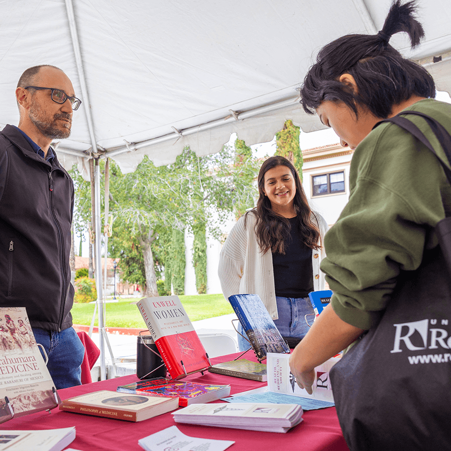 a group of people standing around a table with books