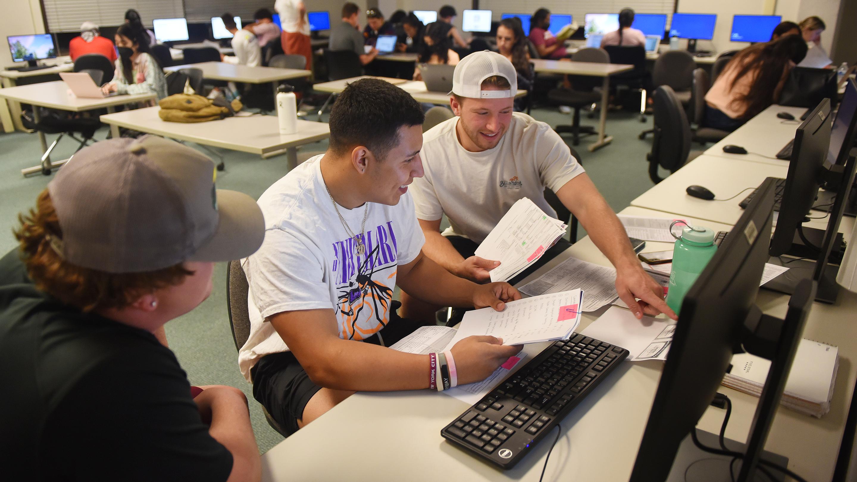 a group of people sitting at a desk with computers