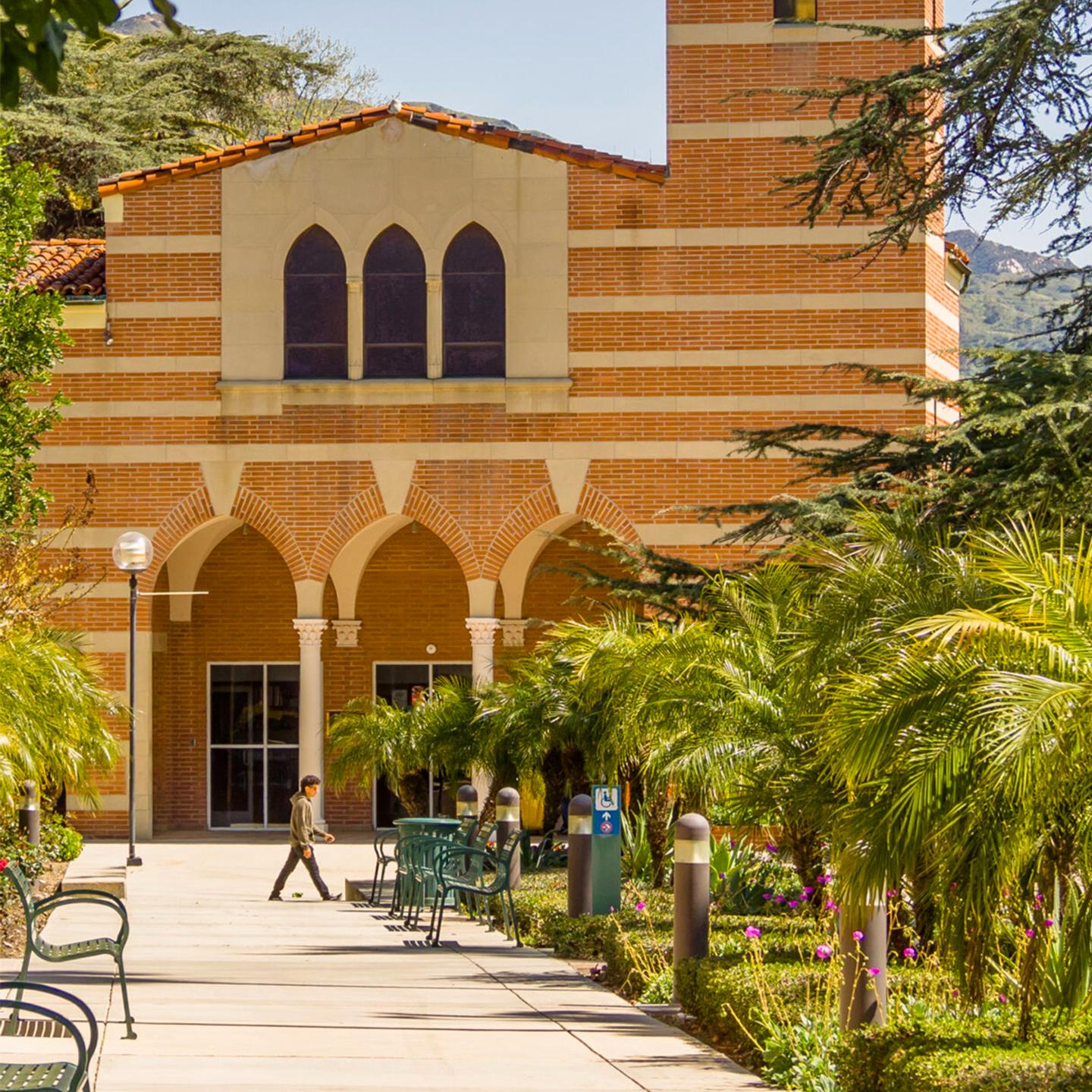 a building with trees and a person walking in front of it