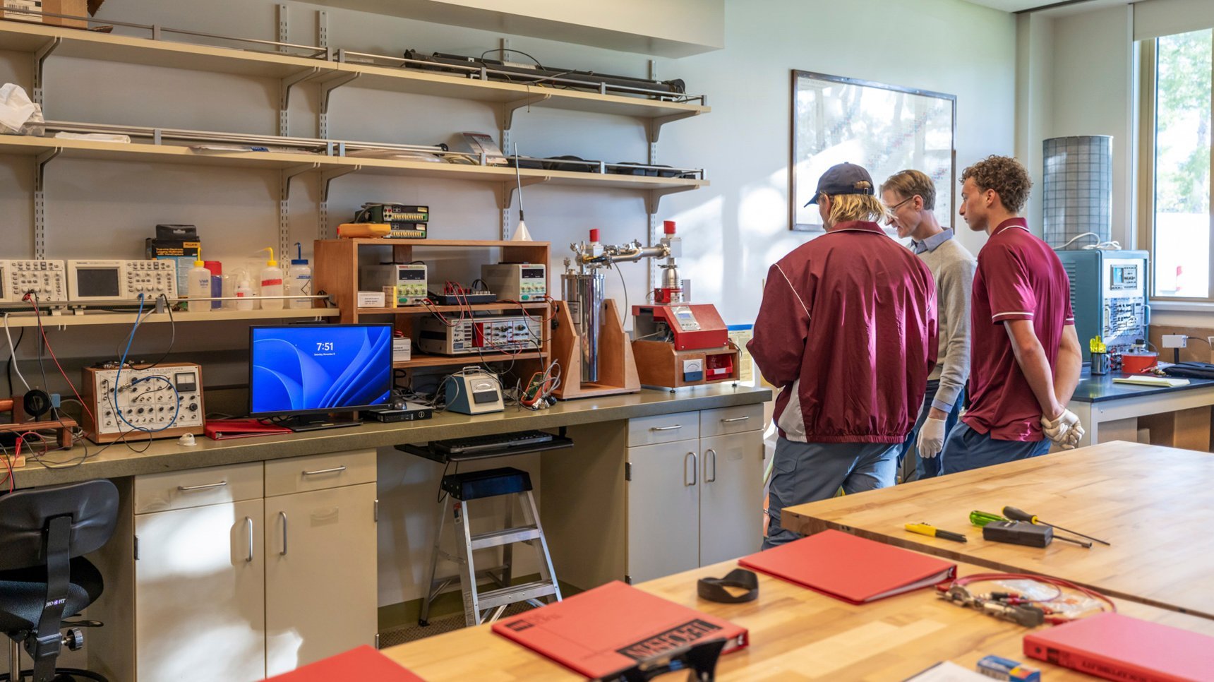 a group of men standing in a room with a computer