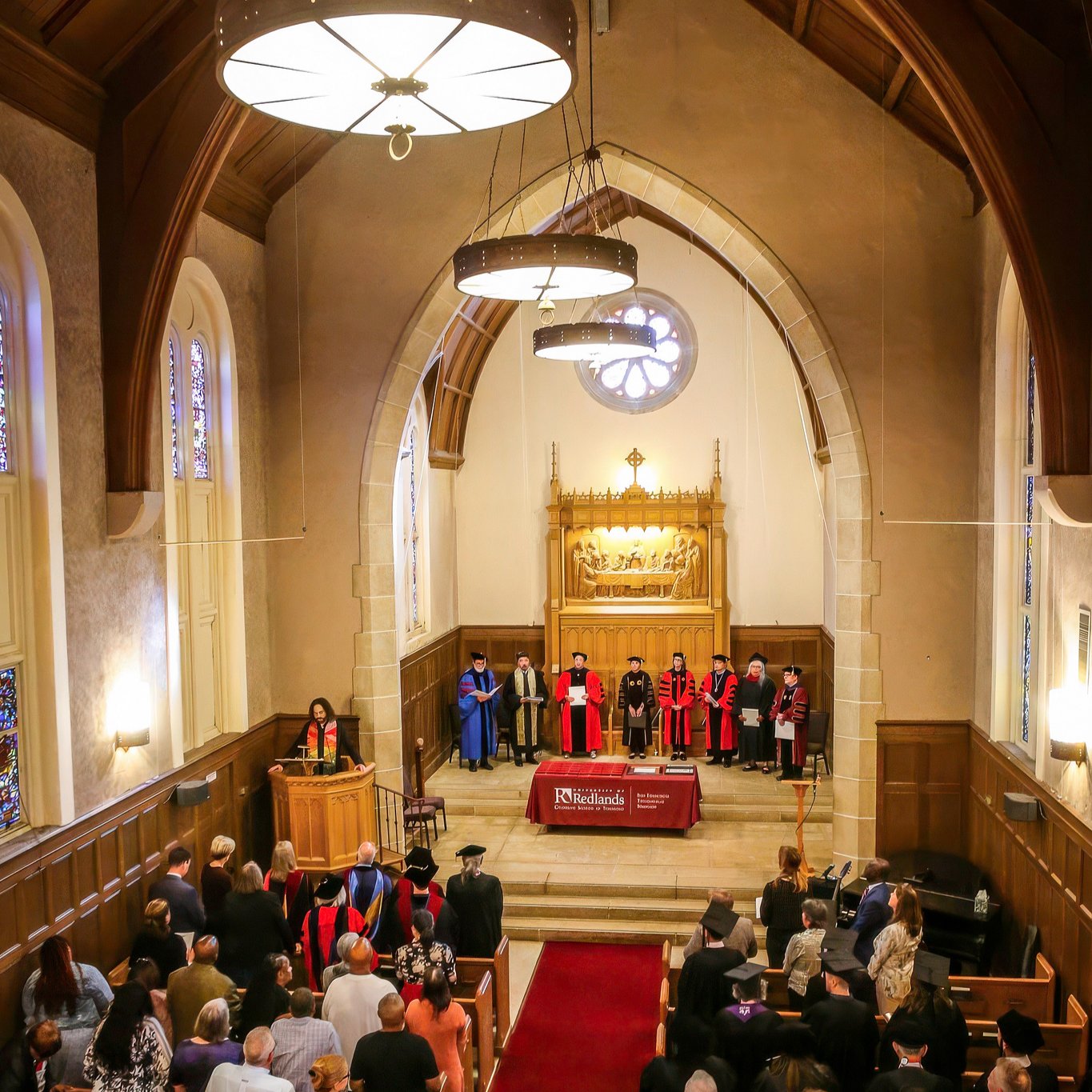 Friends and family standing up for Commencement at a chapel.