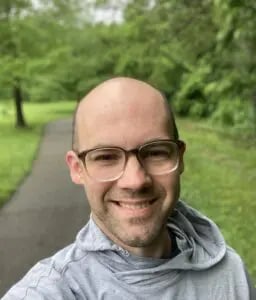 a man wearing glasses and a grey sweatshirt