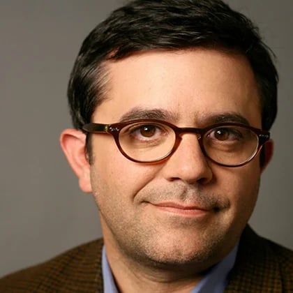 a man wearing glasses and a brown jacket