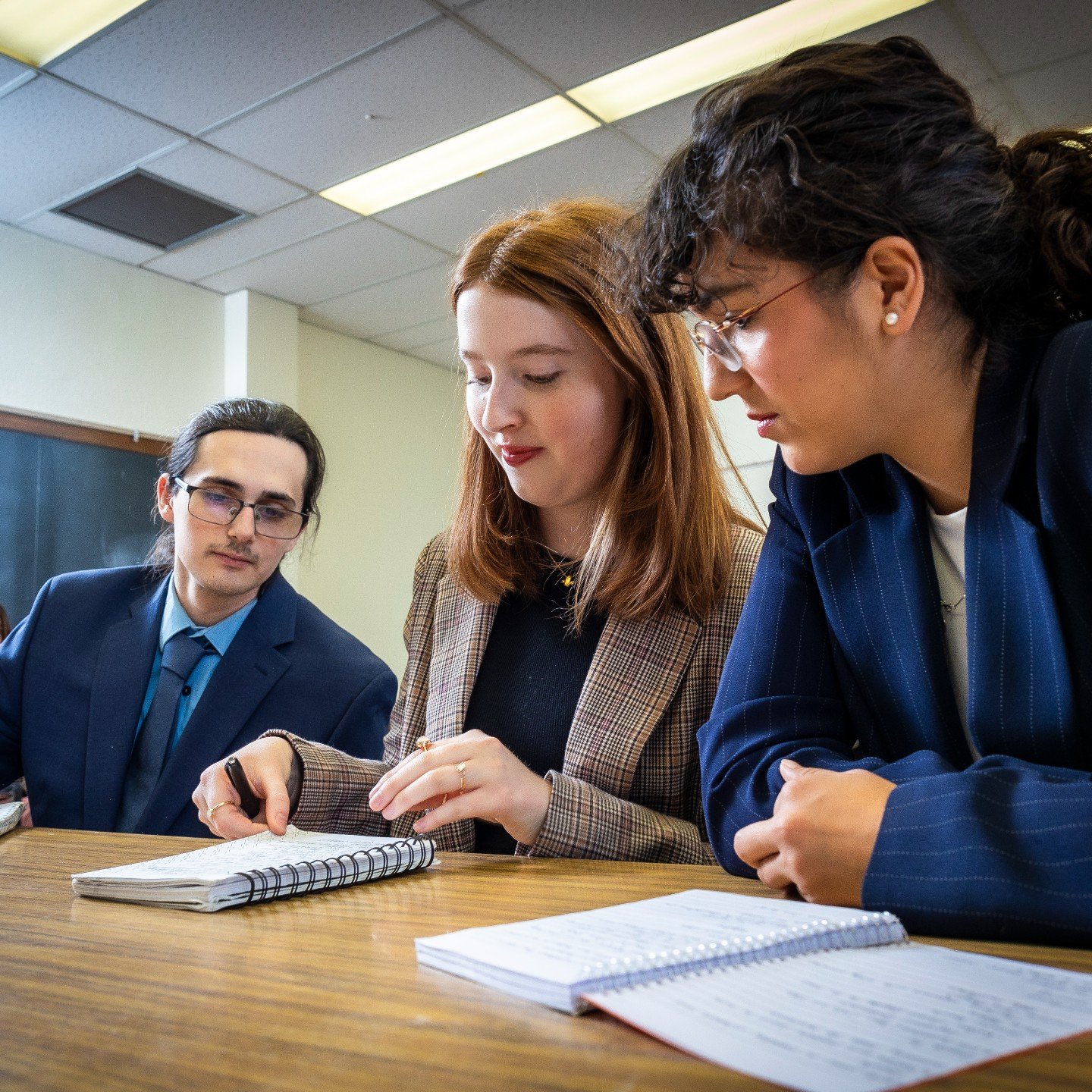 a group of people sitting at a table looking at a notebook