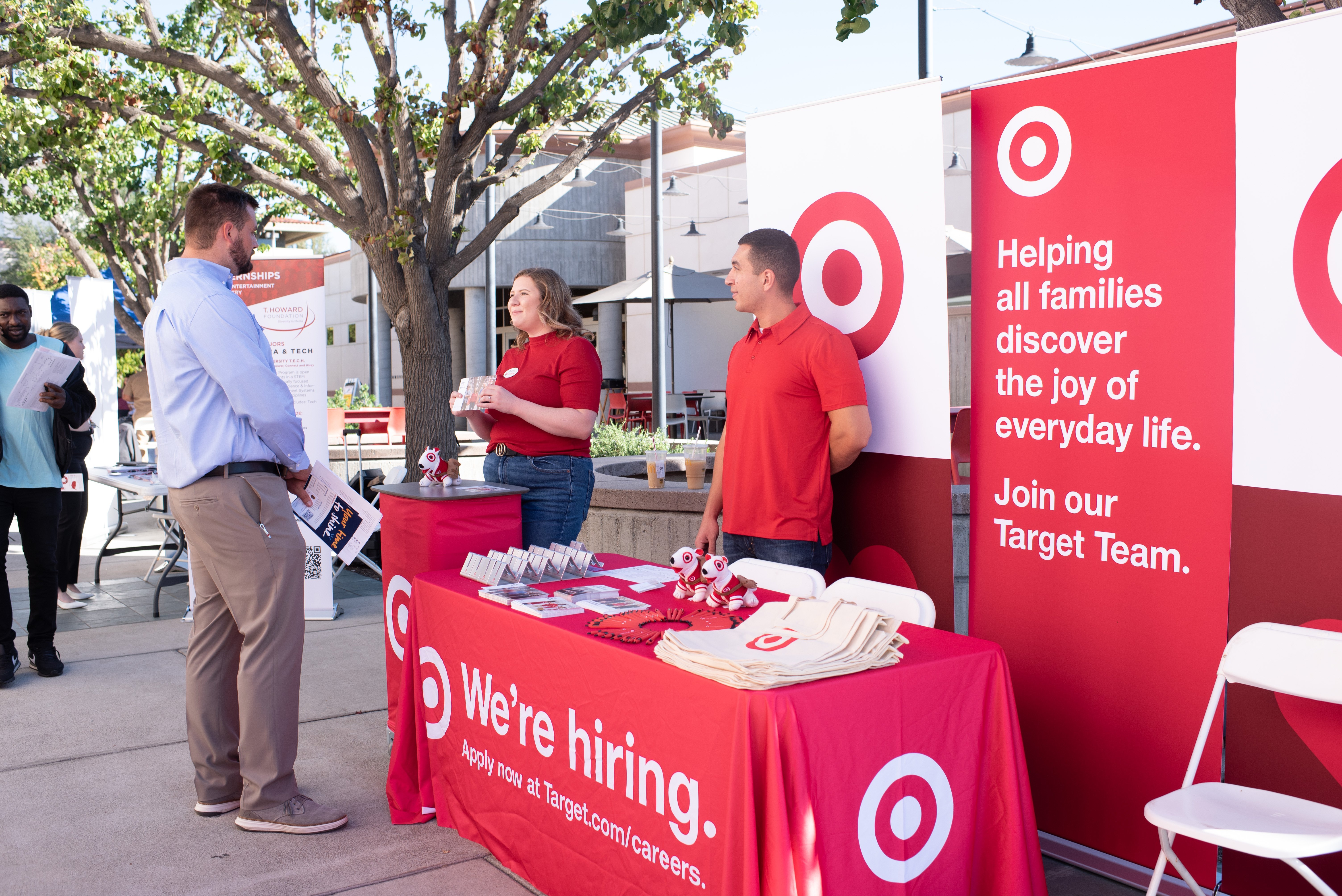 a group of people standing next to a table with red and white signs