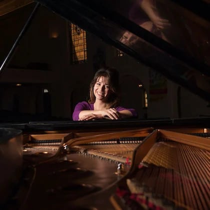a woman leaning on a piano