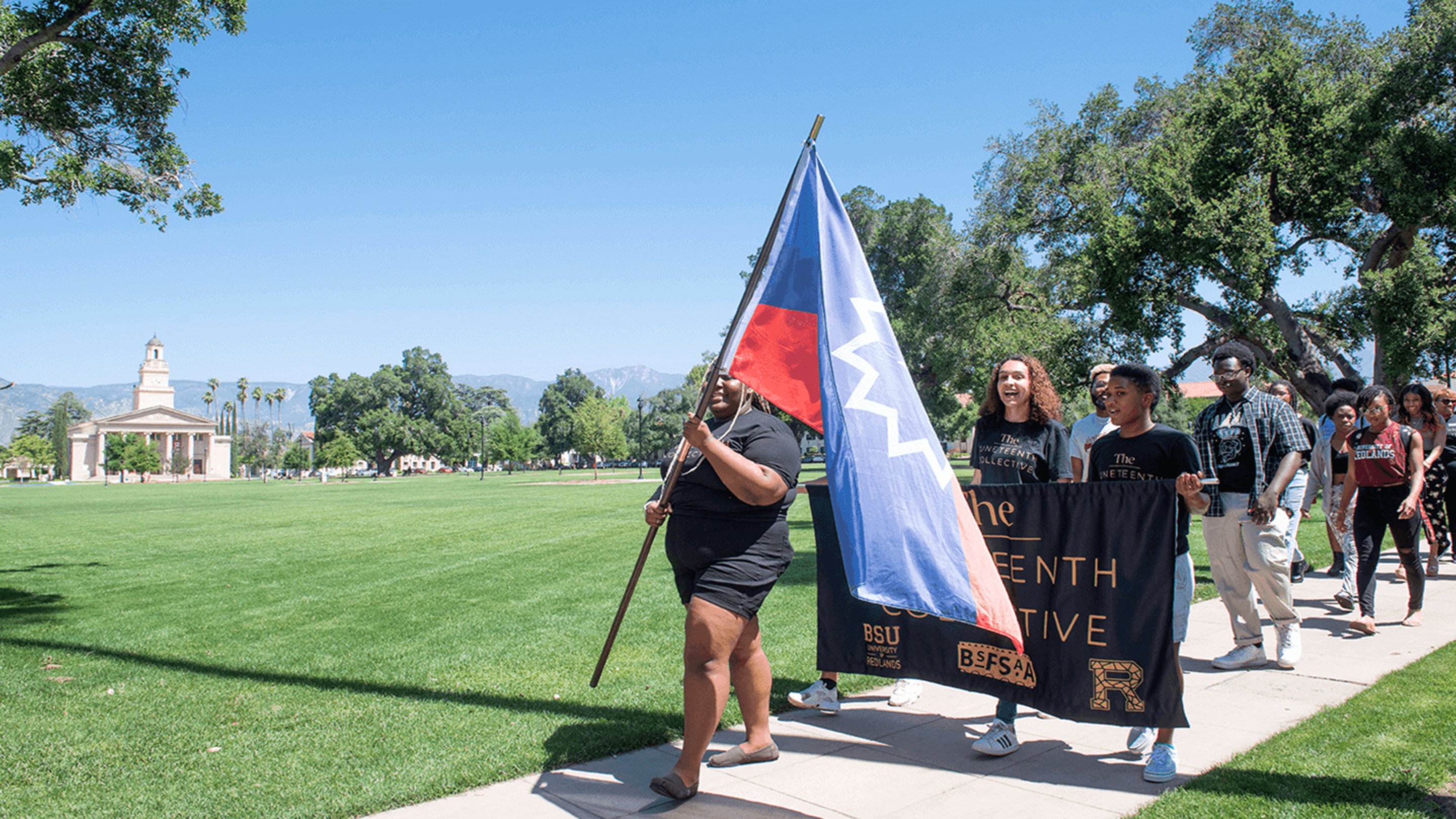 a group of people standing on a sidewalk holding a flag