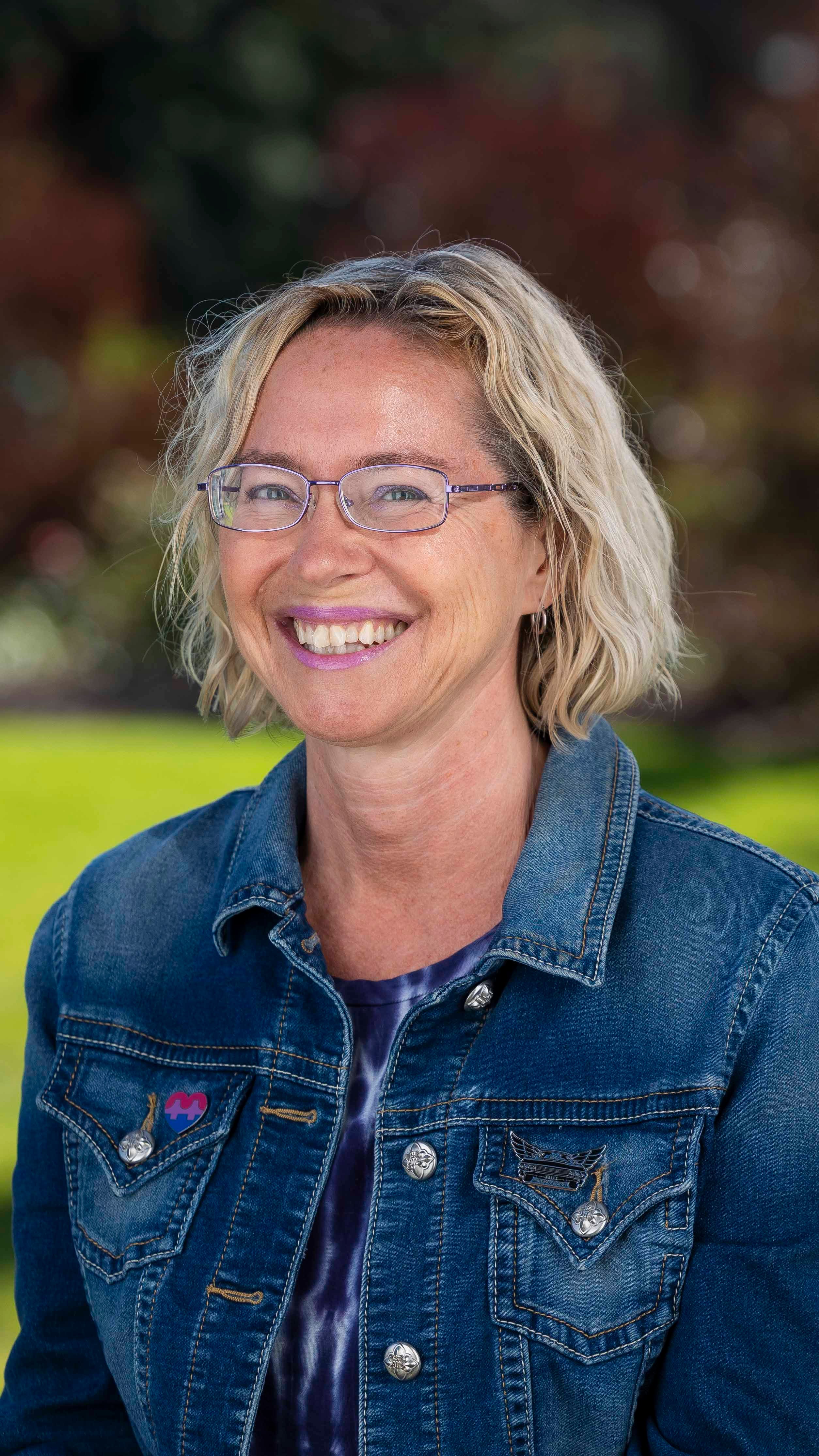 a woman wearing glasses and a denim jacket