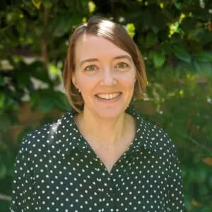 a woman smiling in front of a tree