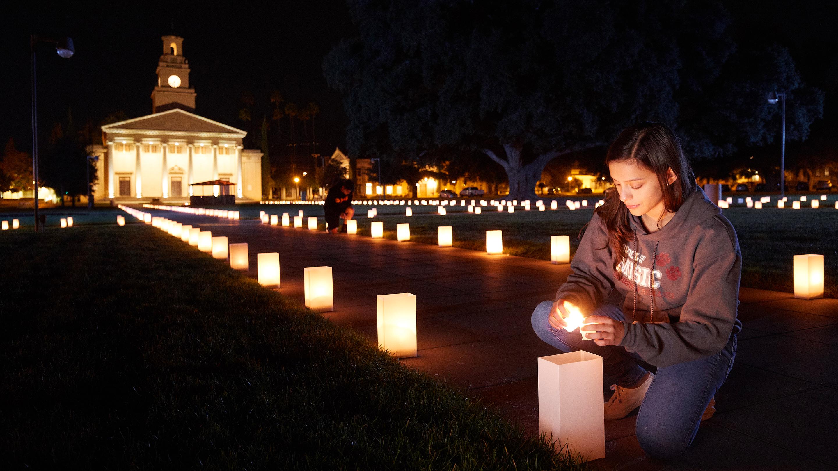 a woman sitting on a sidewalk with a candle in the middle