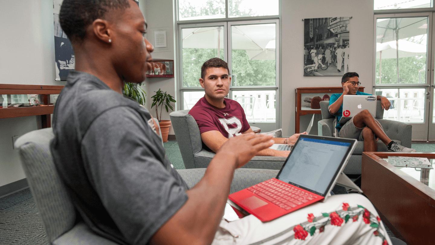 a group of people sitting around a table with a laptop