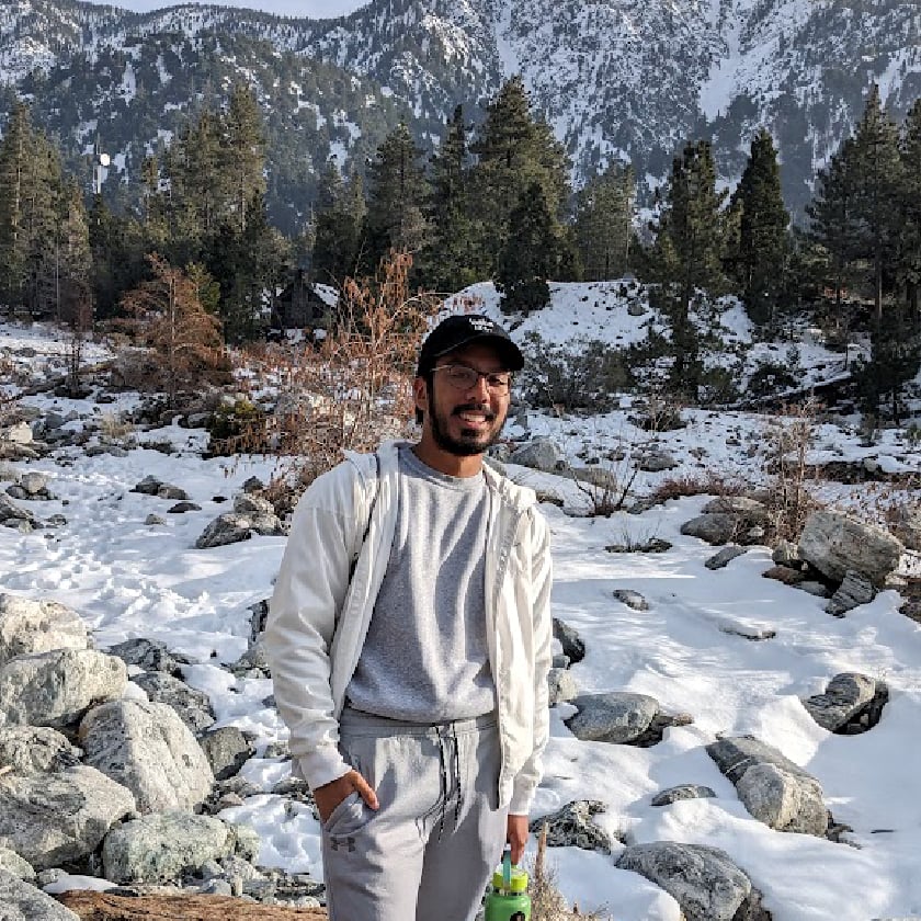 a man standing in snow with trees and mountains in the background