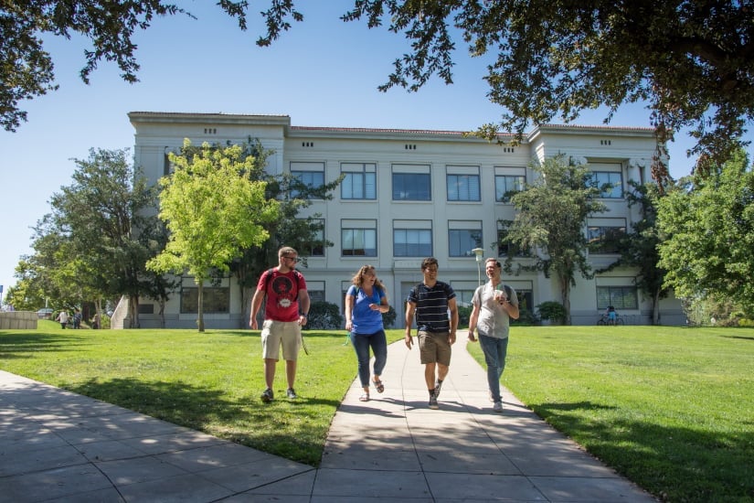 a group of people walking on a sidewalk in front of a building