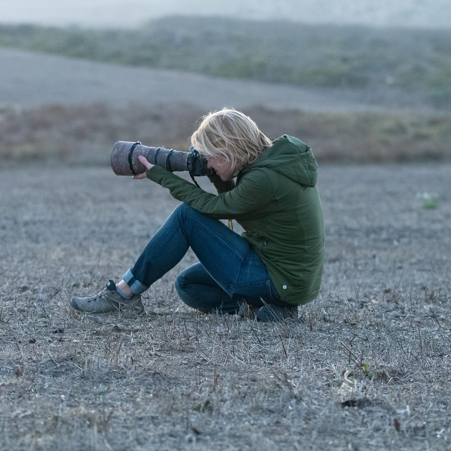 a woman sitting on the ground holding a camera