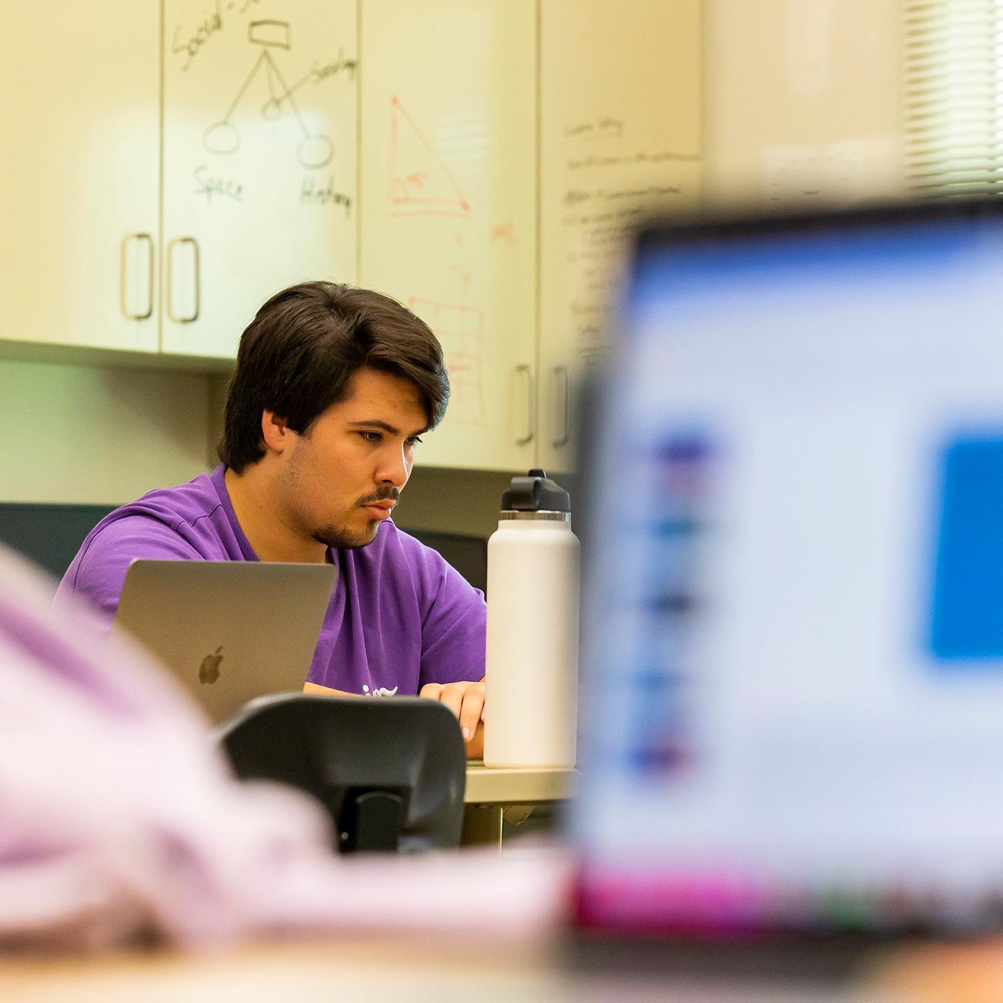 a man sitting at a desk with a laptop