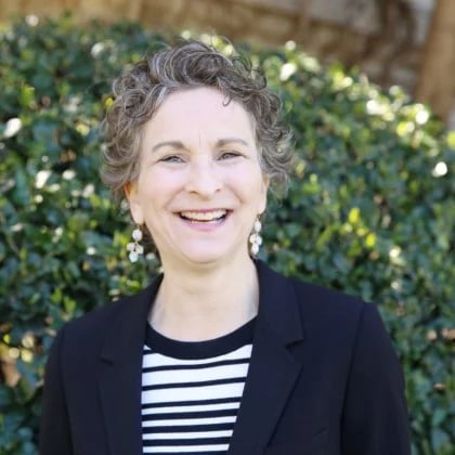 a woman smiling in front of a bush