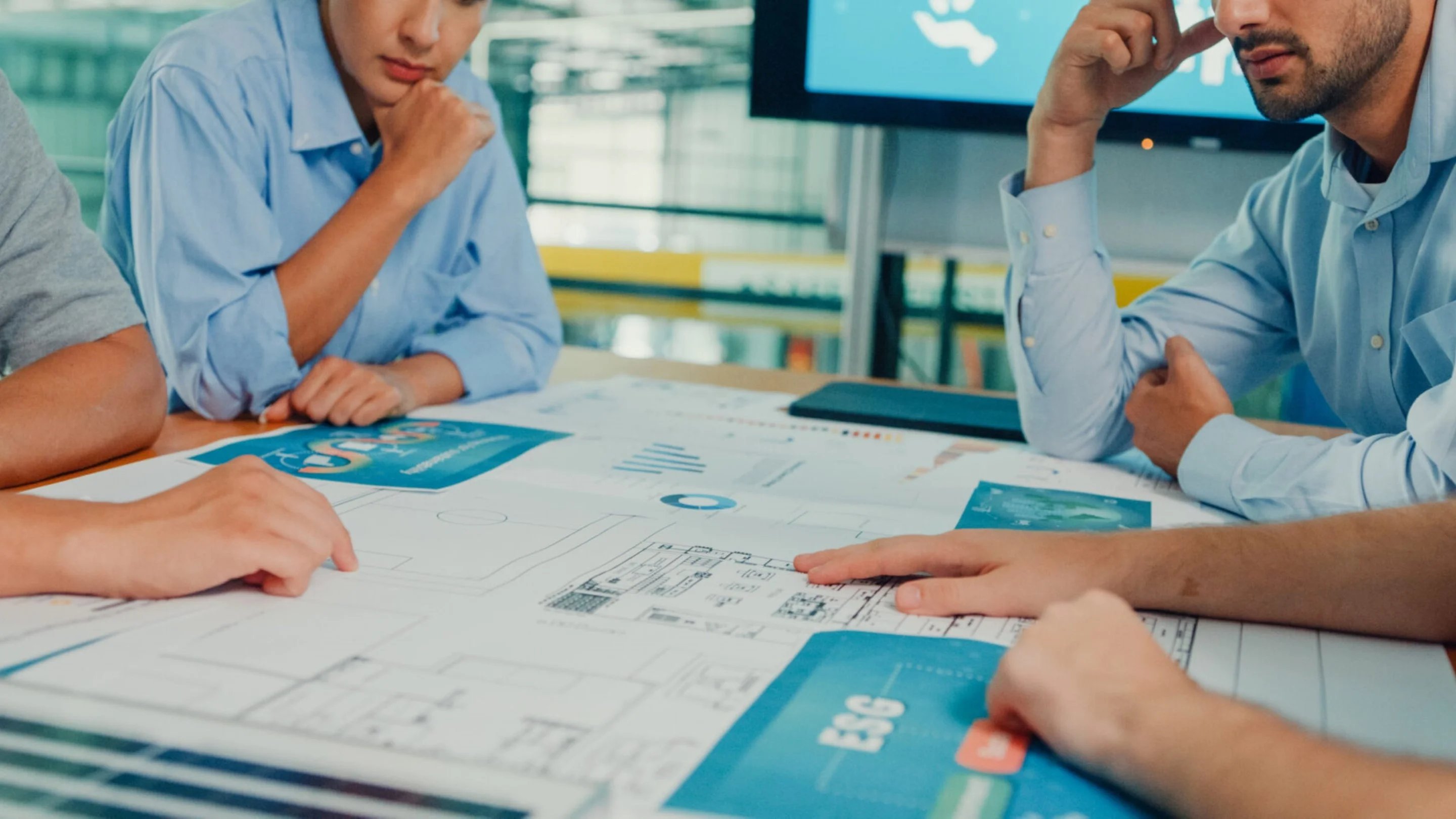 a group of people sitting at a table looking at a blueprint
