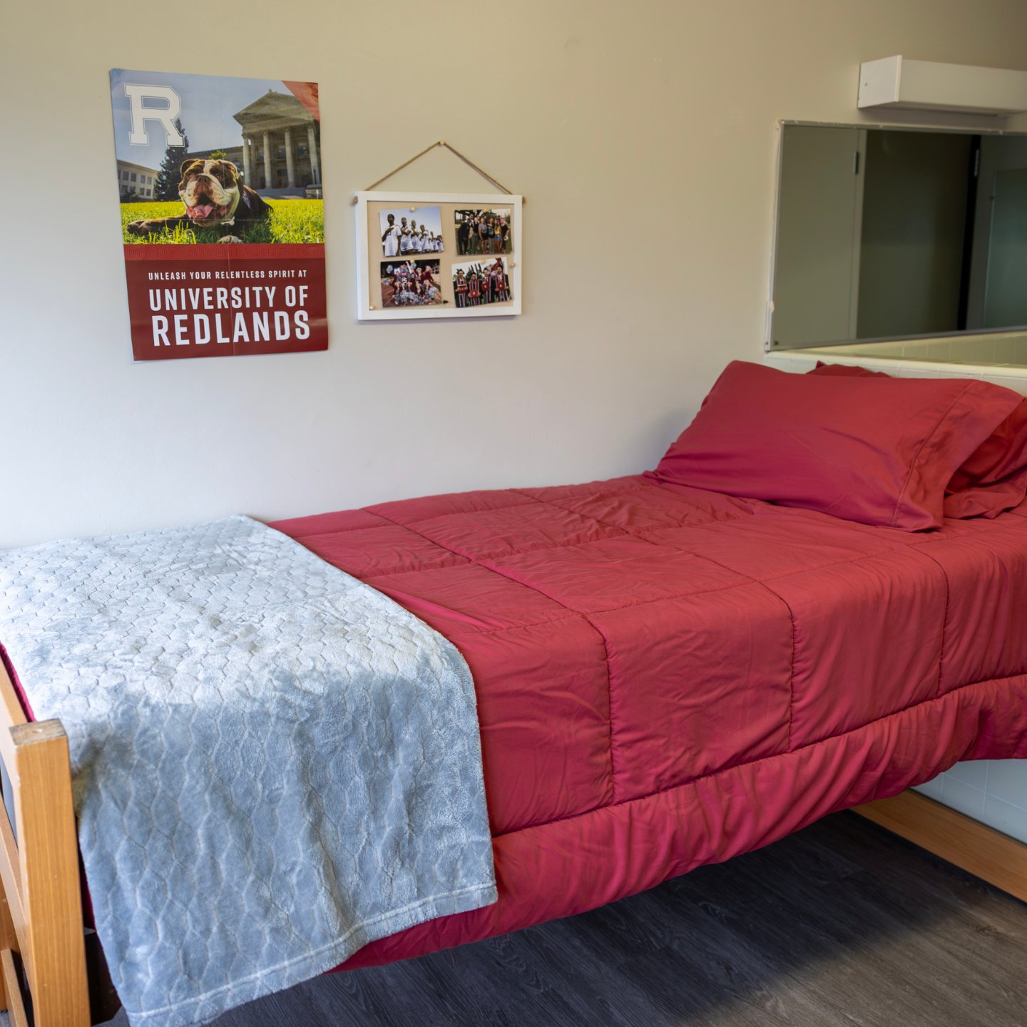 a bed with red sheets and a poster on the wall