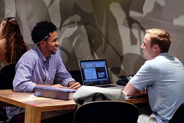 a group of men sitting at a table with a laptop