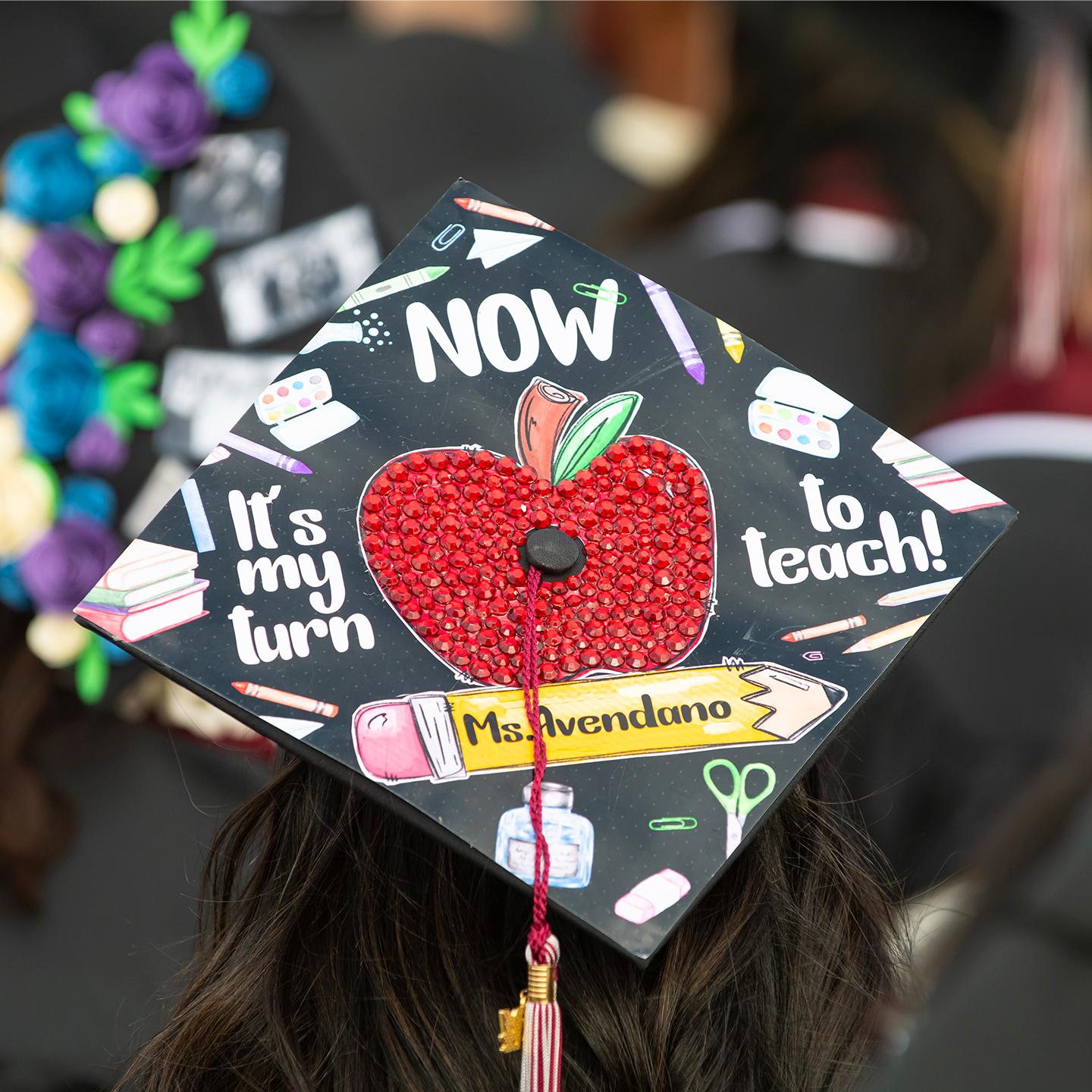 a graduation cap with a red apple on the back