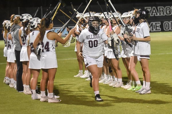 a group of girls in white uniforms holding sticks